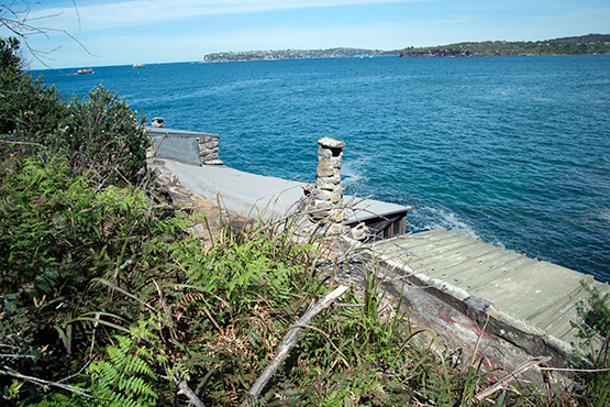 The path leads beside the roofs of the first group of stone huts at Craters Cove, Sydney